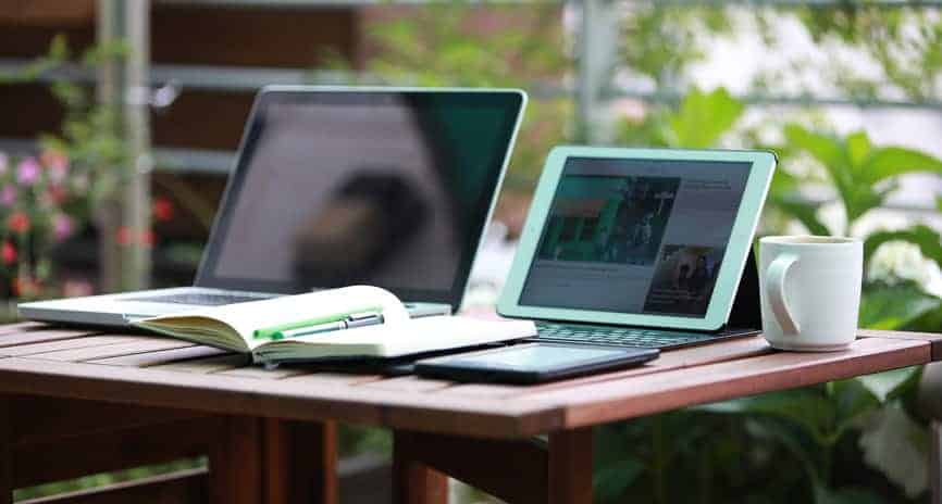 Computadores e tablet em ambiente de trabalho ao ar livre.