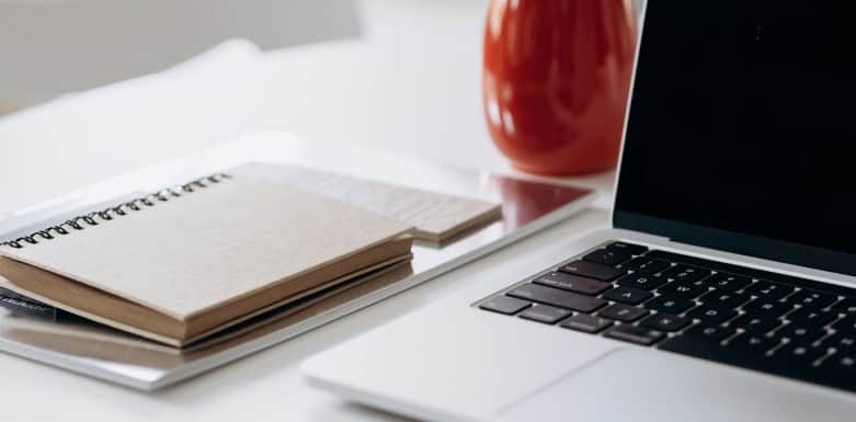 Como produzir conteúdos de qualidade? Conheça o processo de criação da Gear SEO Imagem de notebook aberto com caderno ao lado