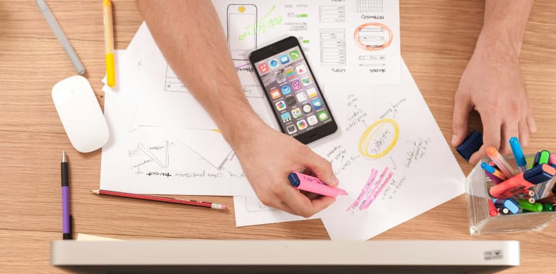 Como planejar um site? Pessoa fazendo anotações na folha sulfite.