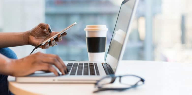 Como configurar o CMS Mulher digitando no computador e segurando o celular com a outra mão.