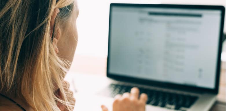 Hub de conteúdo: conheça esse tipo de página Mulher de costas, com a mão no teclado do notebook.