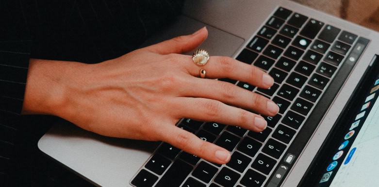 Palavra-chave: saiba tudo sobre esse recurso Mão, com anel no dedo indicador, digitando no computador.