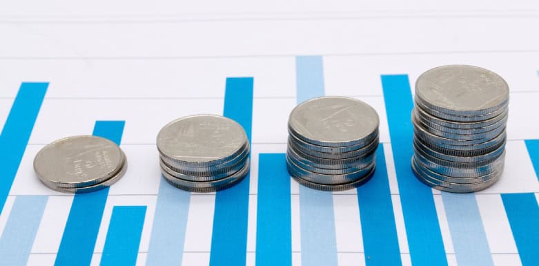 Taxa de conversão: tudo sobre esse conceito Gráfico de barras com pilhas de moedas em cima.