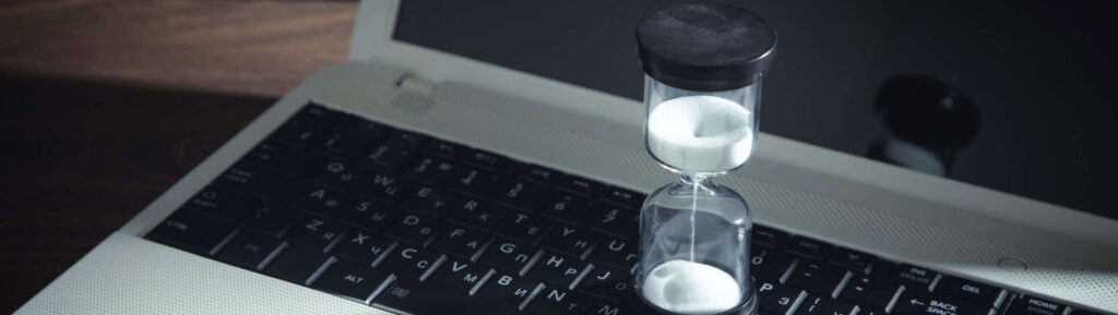 Ampulheta em cima do teclado de computador.