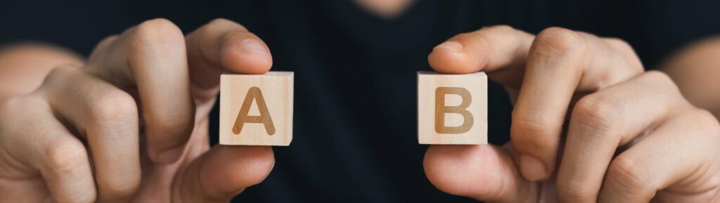 Mãos segurando blocos de madeira com as letras A e B.