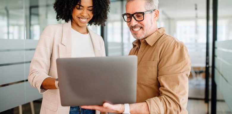 Como aparecer no Google Shopping? Descubra Homem e mulher sorrindo enquanto olham para o computador.