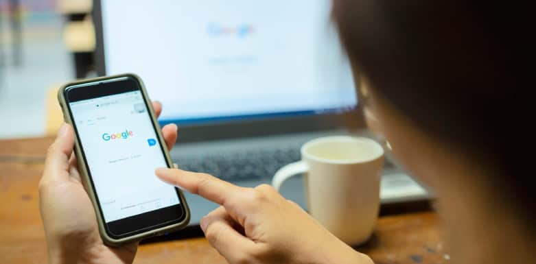 Como aparecer no Google Shopping? Descubra Mulher olhando o Google pelo celular.