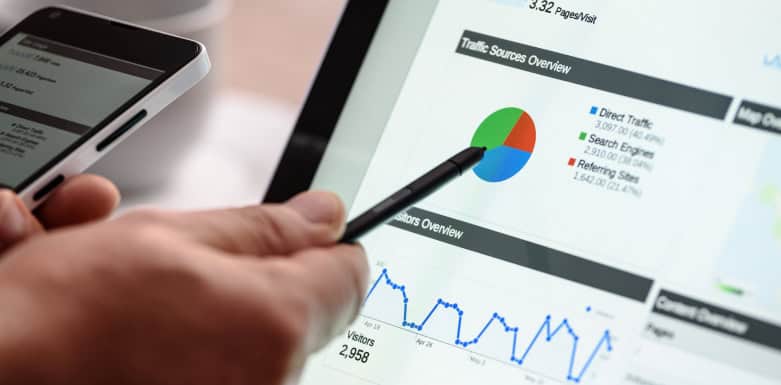 Como aumentar o tráfego do site: veja as principais práticas Mão com lápis apontando para gráfico.