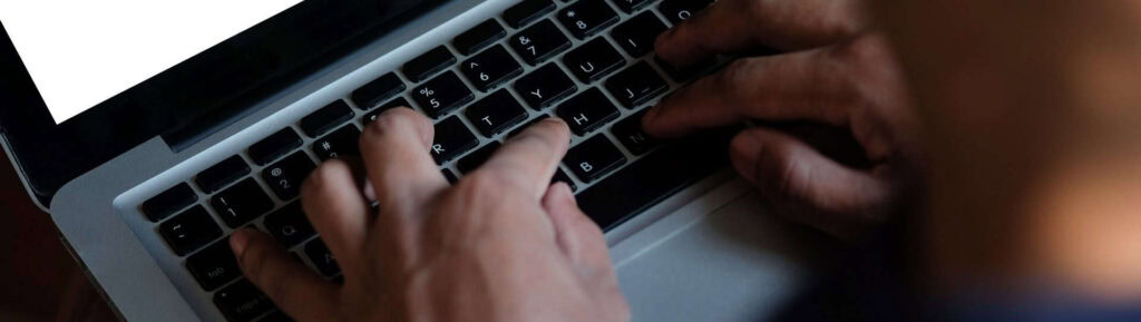 Mãos digitando no teclado do computador.