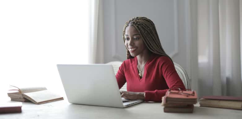 Prefetching: conheça tudo sobre a técnica! Mulher de blusa vermelha usando o notebook numa mesa ampla.