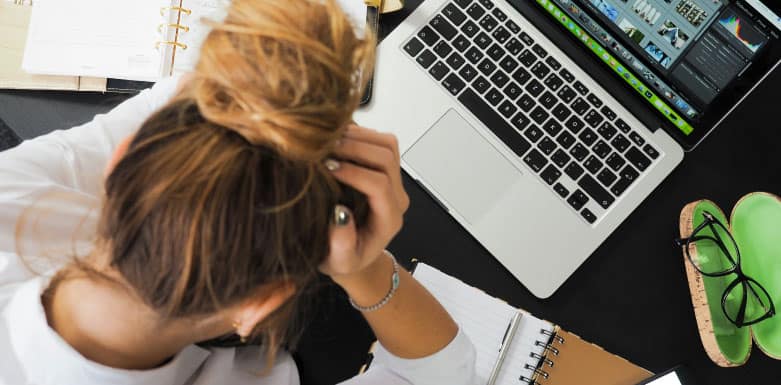 Quais são as técnicas de black hat e como elas são prejudiciais para SEO? Conheça as principais Mulher com a mão na cabeça enquanto olha para o computador.