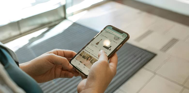 Como o SEO afeta o funil de vendas? Descubra e aumente o seu potencial de vendas Mãos segurando celular aberto em ecommerce.