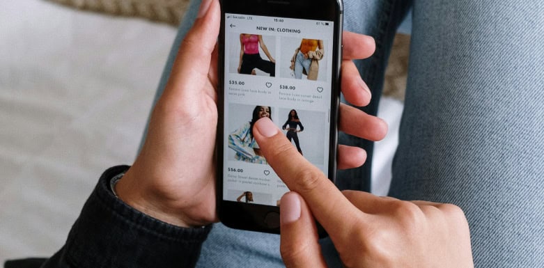 Estratégia para Black Friday: SEO que gera resultados reais Mãos segurando celular aberto em página de e-commerce de roupas femininos.