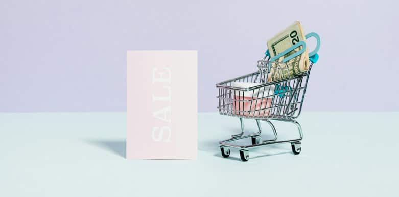 Estratégia para Black Friday: SEO que gera resultados reais Carrinho de compras em miniatura ao lado de cartão com escrita de "promoção".