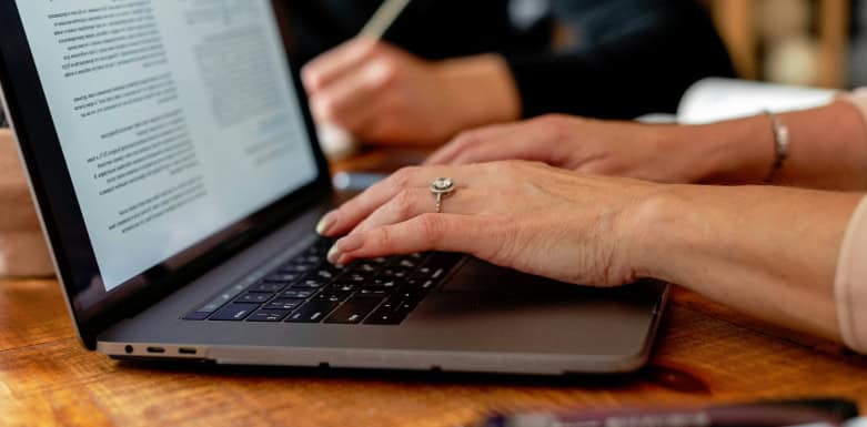 Palavras de transição para SEO: para otimizar seu texto Mãos digitando texto em notebook.