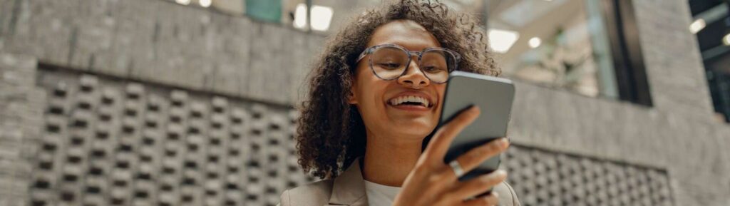 Mulher sorrindo para o celular.
