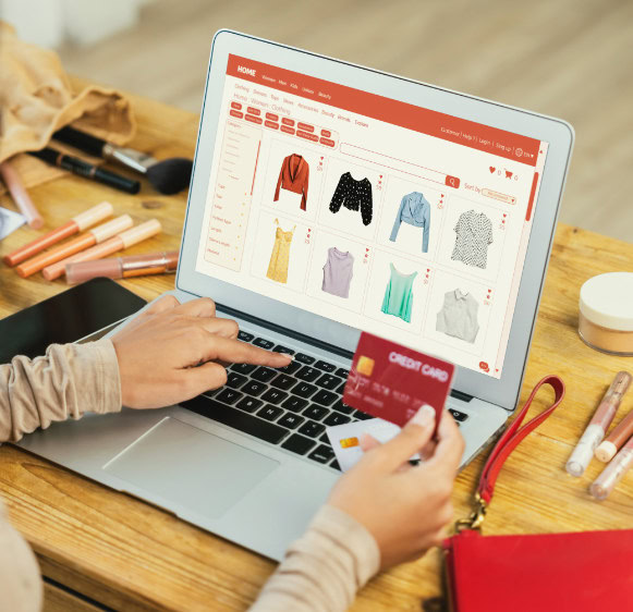 Pessoa faz compra online de roupas usando cartão de crédito em laptop.